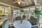 Screened in porch with dining table overlooking the community pond and fountains